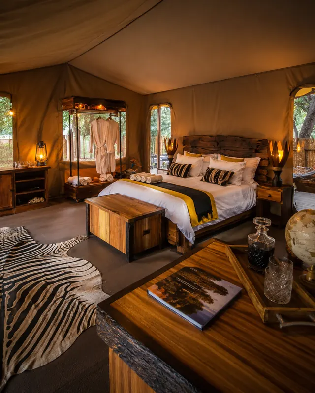 Luxury safari tent bedroom with timber chest, zebra hide rug and canvas walls
