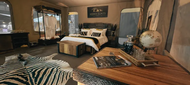 Safari tent interior with king bed, zebra rug, coffee table and wardrobe